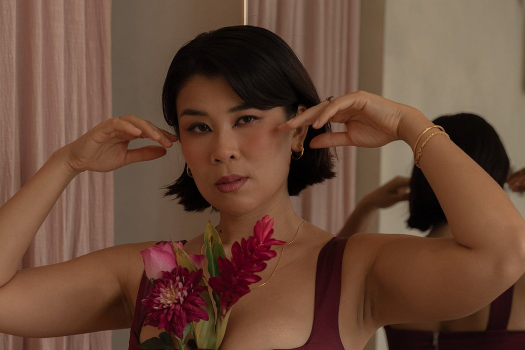 Nadia in a burgundy corset with flowers, hands framing her face